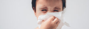 kid blowing his nose to indicate allergy symptoms