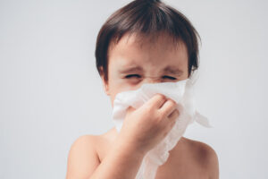 kid blowing his nose to indicate allergy symptoms